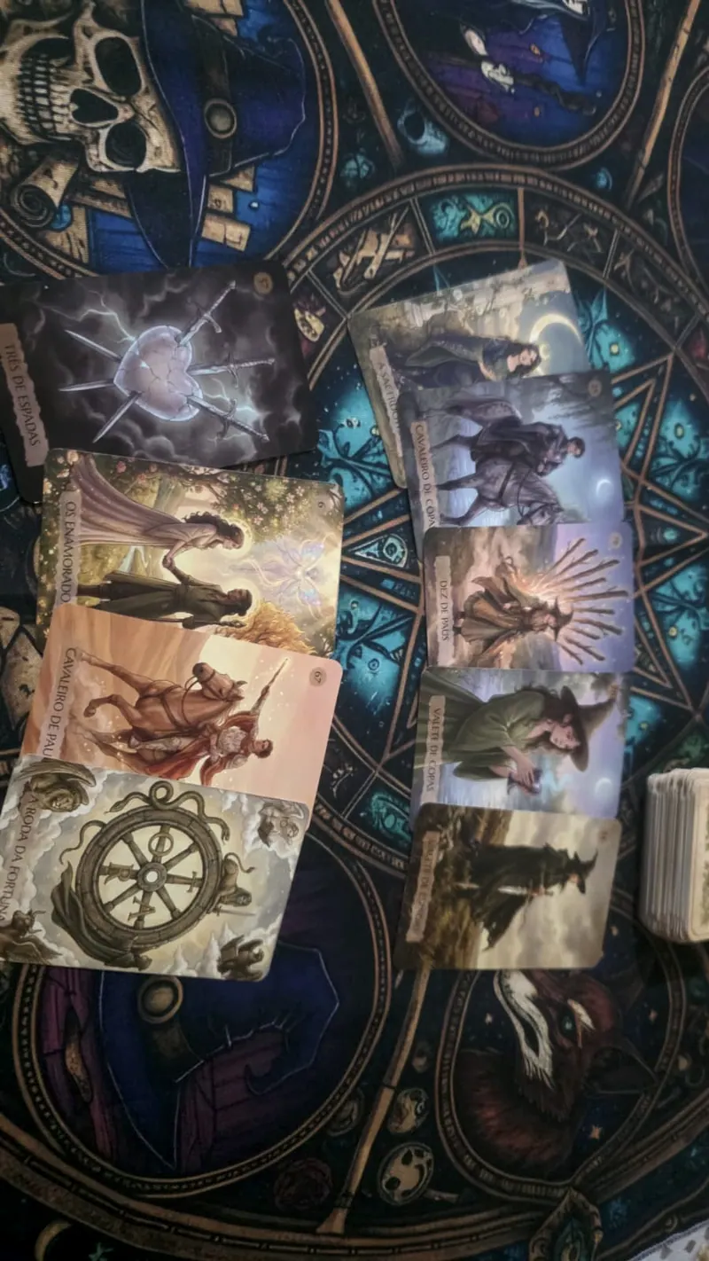 Tiragem de tarôt sobre toalha azul e dourada, com cartas Os Enamorados e A Roda da Fortuna